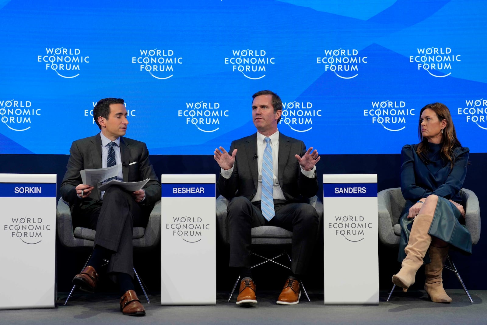 Kentucky Governor Andy Beshear, center, gestures besides Arkansas Gov. Sarah Huckabee Sanders at the Annual Meeting of World Economic Forum in Davos, Switzerland, Thursday, Jan. 23, 2025. (AP Photo/Markus Schreiber)