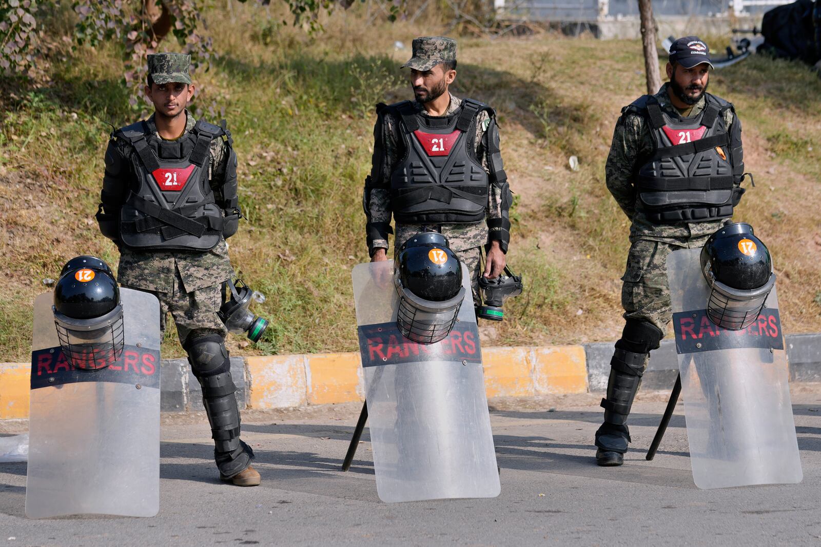 Paramilitary soldiers stand guard with riot gears at a road barricaded with shipping containers ahead of a planned rally by supporters of imprisoned former Prime Minister Imran Khan's Pakistan Tehreek-e-Insaf party, in Islamabad, Pakistan, Sunday, Nov. 24, 2024. (AP Photo/Anjum Naveed)