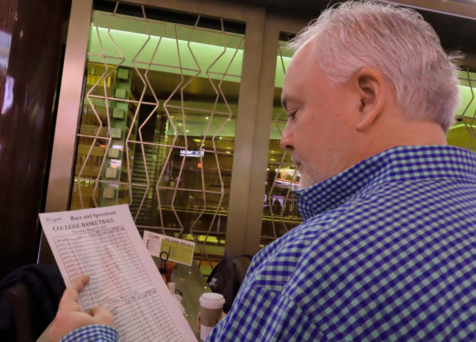 FILE - Mike McMahon of Long Island, NY reads a betting sheet at the Borgata casino in Atlantic City NJ on March 17, 2022, the first day of the March Madness college basketball tournament. (AP Photo/Wayne Parry,File)