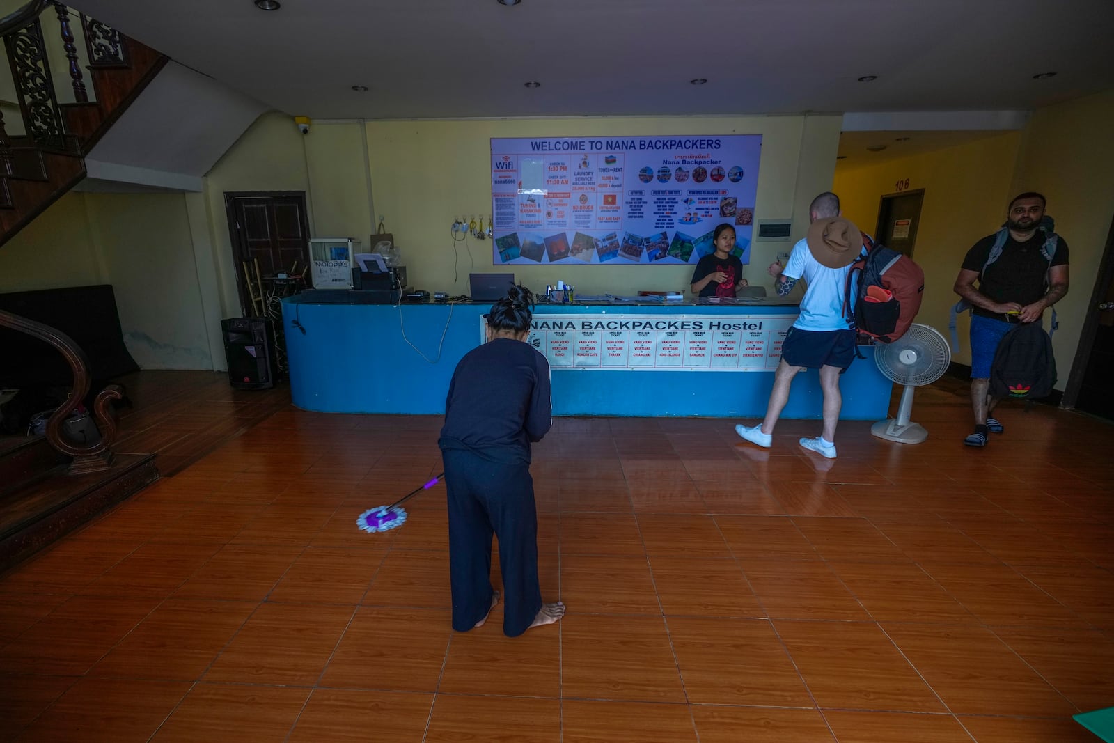 A woman swipes the floor as foreign tourists check out of Nana Backpack hostel in Vang Vieng, Laos, Tuesday, Nov. 19, 2024. (AP Photo/Anupam Nath)