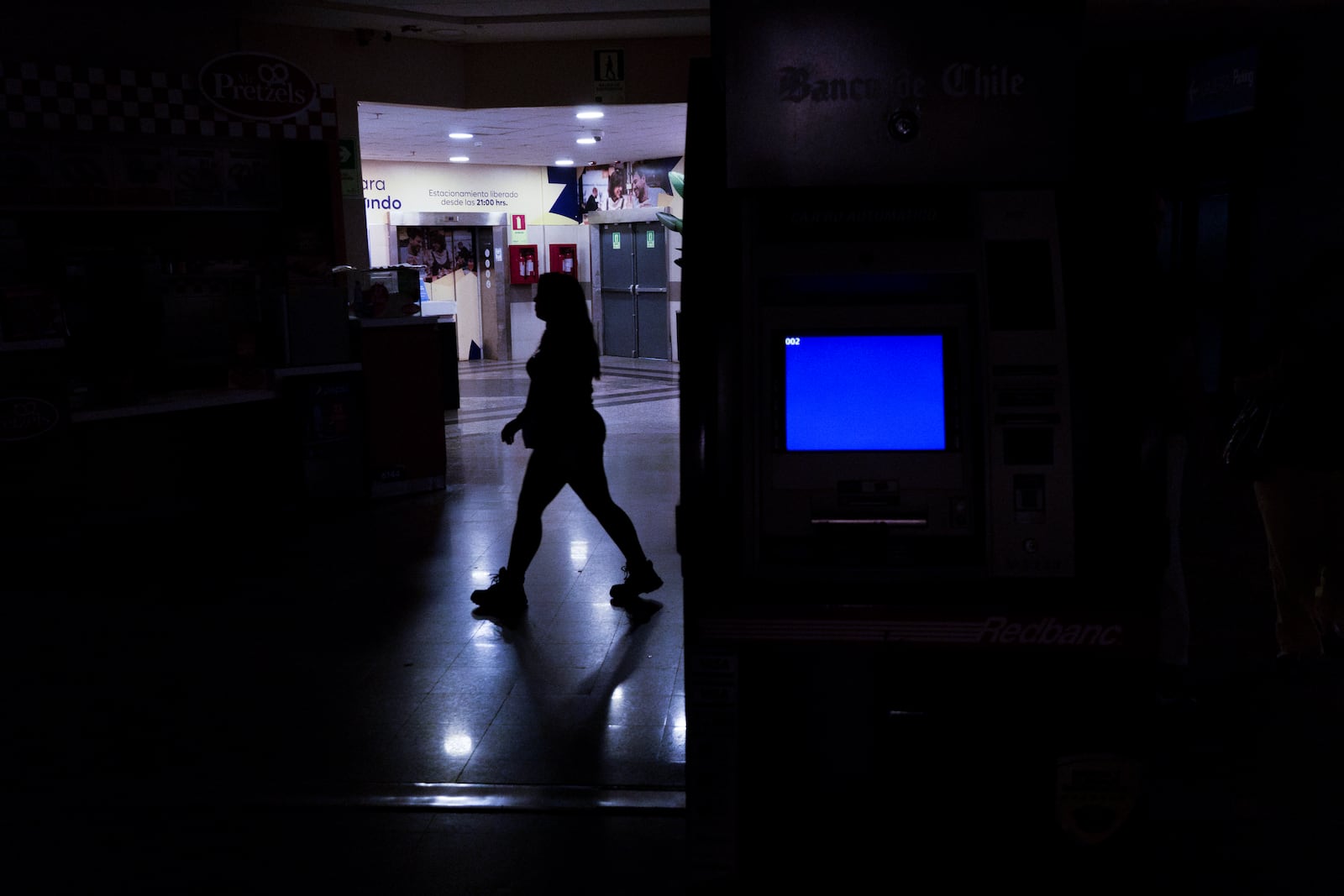 A woman walks through a shopping mall during a power outage in Santiago, Chile, Tuesday, Feb. 25, 2025. (AP Photo/Matias Basualdo)