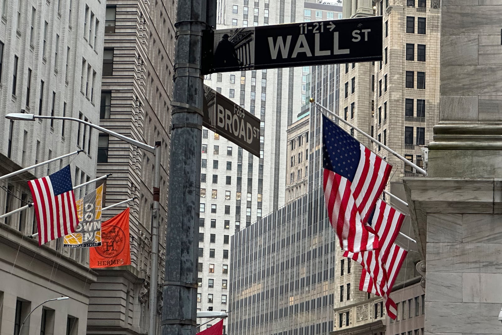 FILE - American flags hang from the front the New York Stock Exchange, right, on April 11, 2024, in New York. (AP Photo/Peter Morgan, File)