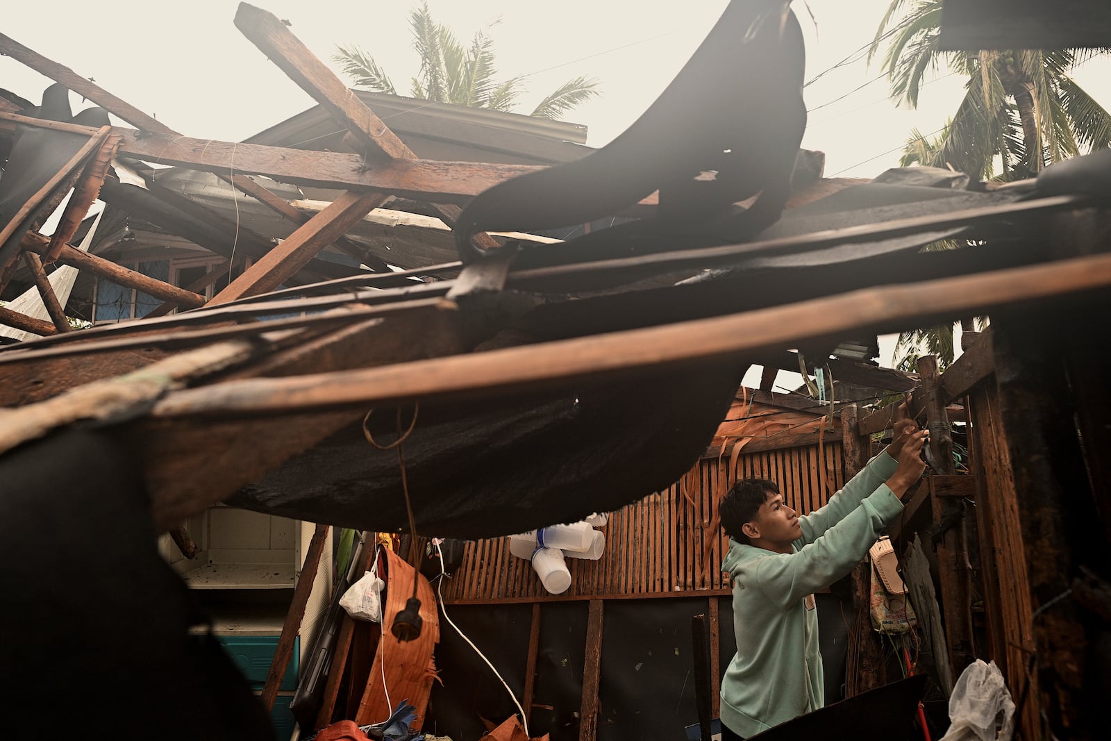 A resident checks belongings from his damaged home that was blown off by strong winds caused by Typhoon Man-yi in the municipality of Baler, Aurora province, northeastern Philippines Monday, Nov. 18, 2024. (AP Photo/Noel Celis)