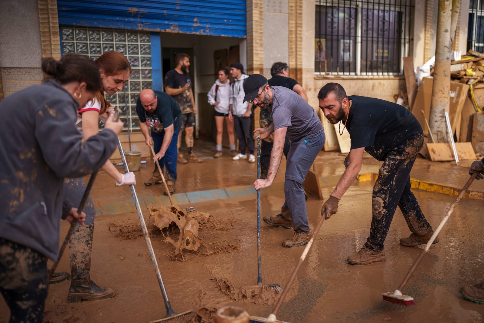 People clean the street of mud in an area affected by floods in Sedavi, Spain, on Friday, Nov. 1, 2024. (AP Photo/Manu Fernandez)