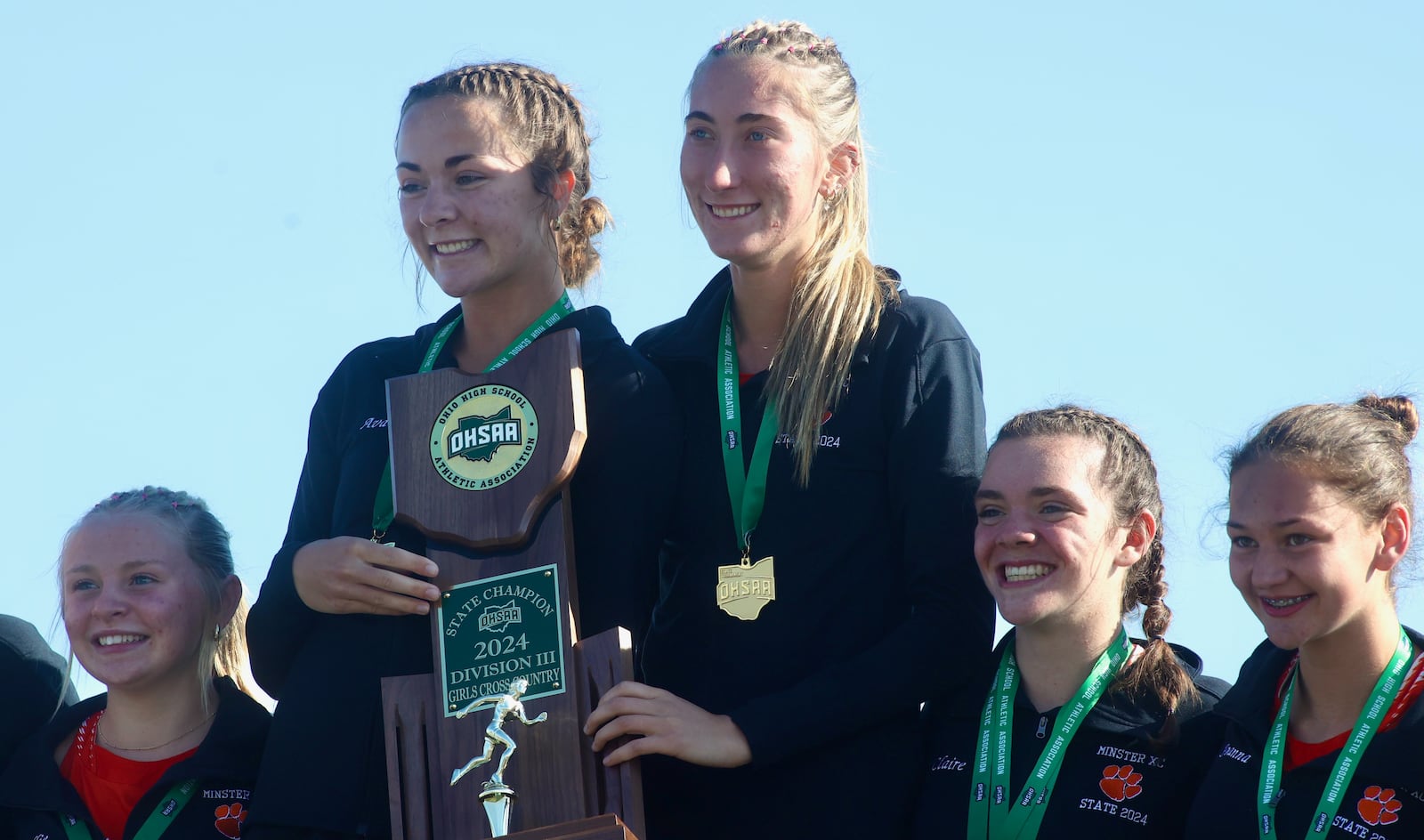 The Minster girls cross country team poses for a photo with the Division III state championship trophy on Saturday, Nov. 2, 2024, at Fortress Obetz in Obetz. David Jablonski/Staff