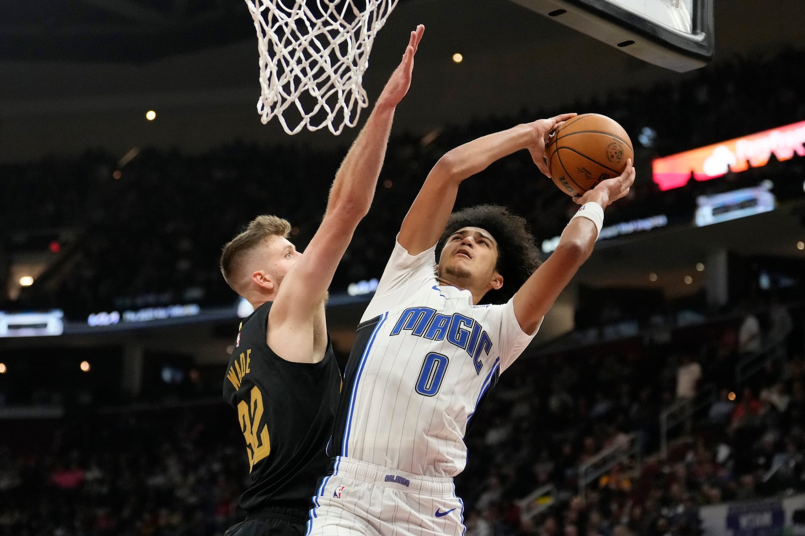 Orlando Magic guard Anthony Black (0) shoots as Cleveland Cavaliers forward Dean Wade (32) defends in the first half of an NBA basketball game, Friday, Nov. 1, 2024, in Cleveland. (AP PhotoSue Ogrocki)