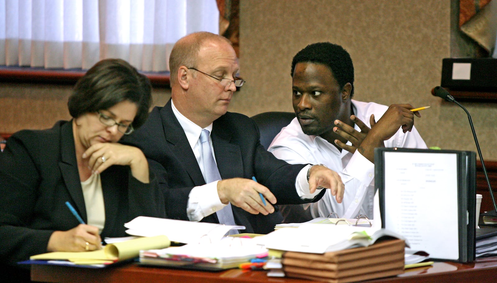 Calvin McKelton, right, talks with attorney Greg Howard Friday as his second attorney Melynda Cook takes notes during the fifth day of his capital murder trial in Butler County Common Pleas Judge Michael Sage's courtroom. McKelton is accused of killing Margaret "Missy" Allen, his girlfriend and Fairfield attorney, as well as Germaine Lamar Evans Sr., who prosecutors say witnessed Allen's strangulation and was killed "execution-style" so he couldn't testify.