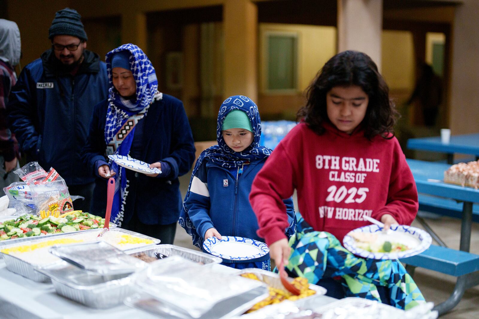 People serve food during a community gathering at a school to discuss plans for Ramadan for members of an Altadena mosque, which was gutted in the Eaton fire, in Pasadena, California, Saturday, Feb. 15, 2025. (AP Photo/Eric Thayer)