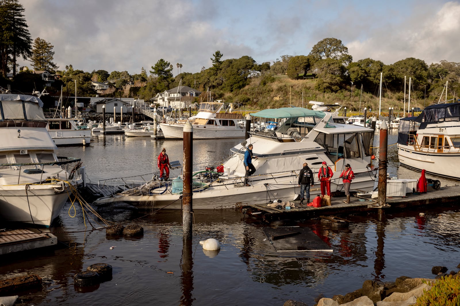 Recovery crews pump water from a semi-submerged boat in Santa Cruz Harbor after it was damaged during high surf in Santa Cruz, Calif., Tuesday, Dec. 24, 2024. (Santa Cruz/San Francisco Chronicle via AP)