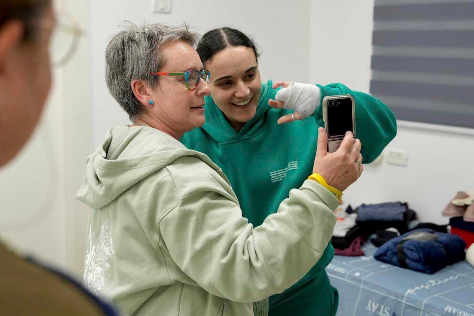 In this photo released by the Israeli Army, Emily Damari, right, and her mother Mandy use a smart phone near kibbutz Reim, southern Israel after Emily was released from captivity by Hamas militants in Gaza, Sunday, Jan. 19, 2025. (Israeli Army via AP)