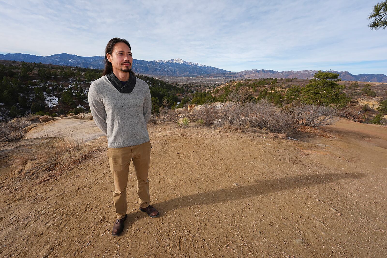 Lane Belone poses with Pikes Peak in the background on an overlook in Palmer Park, Thursday, Dec. 19, 2024, in Colorado Springs, Colo. (AP Photo/David Zalubowski)