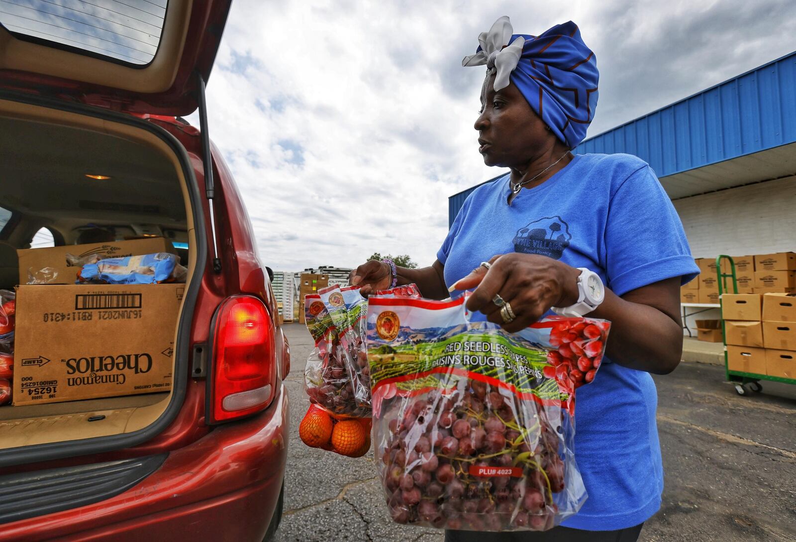 Harristine Dailey loads fruit into a car during a food distribution Wednesday, Aug. 3, 2021, at Village Food Pantry in New Miami. The pantry provides food for nearly 200 families a week. NICK GRAHAM/STAFF