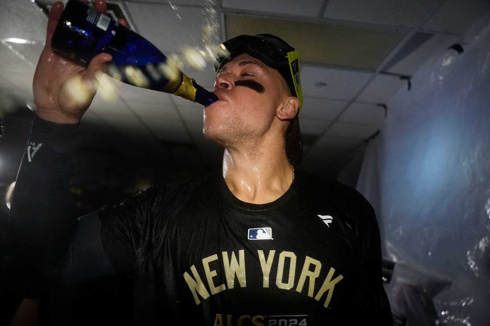 New York Yankees' Aaron Judge celebrates in the clubhouse following a 3-1 victory over the Kansas City Royals in Game 4 of an American League Division baseball playoff series Thursday, Oct. 10, 2024, in Kansas City, Mo. (AP Photo/Reed Hoffmann)