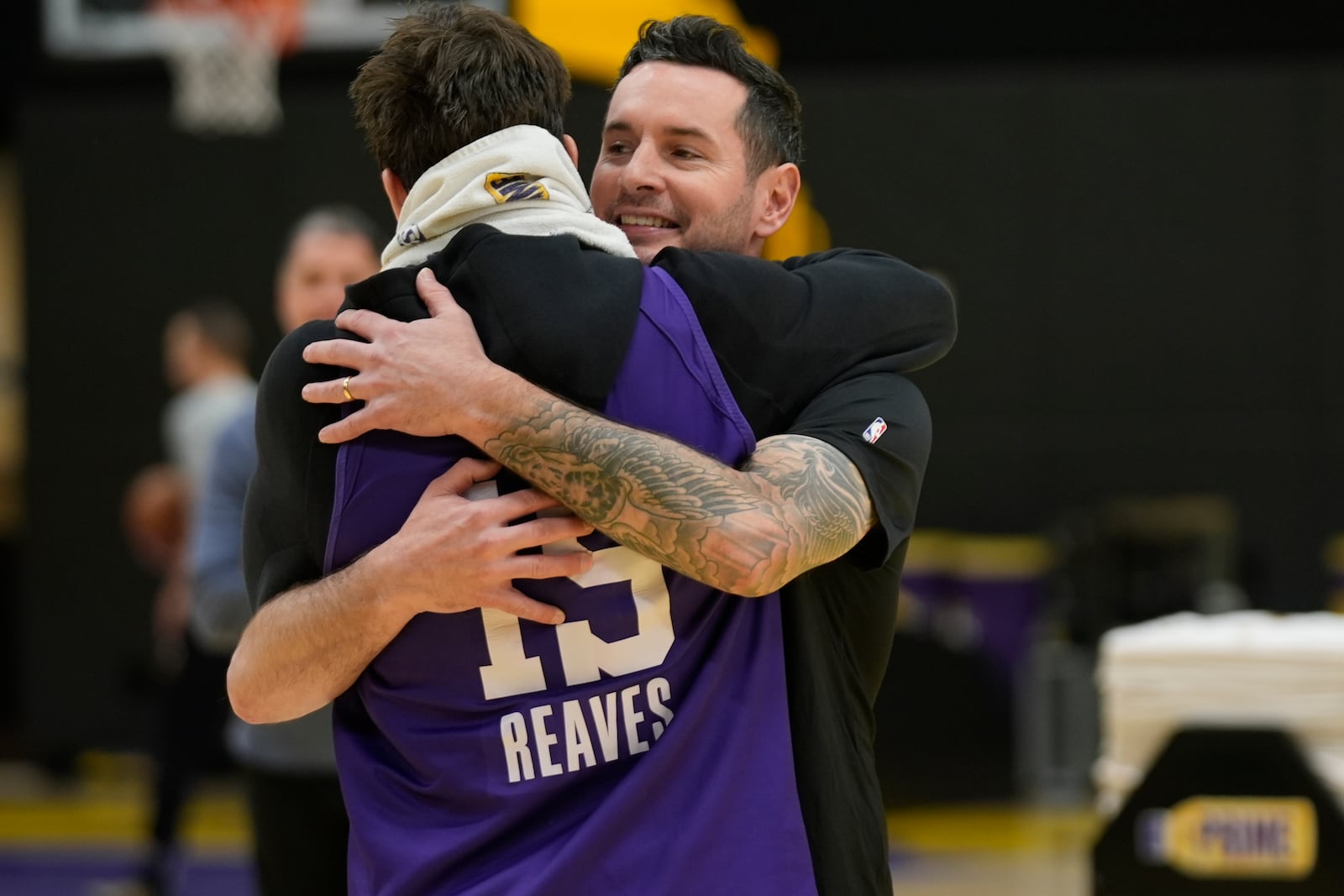 Los Angeles Lakers NBA basketball head coach JJ Redick, right, is hugged by guard Austin Reaves, left before talking to the media about the Pacific Palisades wildfire at a news conference in El Segundo, Calif., Friday, Jan. 10, 2025. (AP Photo/Damian Dovarganes)