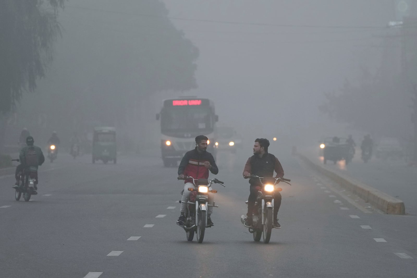 Vehicles and motorcyclists move with headlights on due to reduced visibility caused by smog enveloping the area of Lahore, Pakistan, Wednesday, Nov. 13, 2024. (AP Photo/K.M. Chaudary)