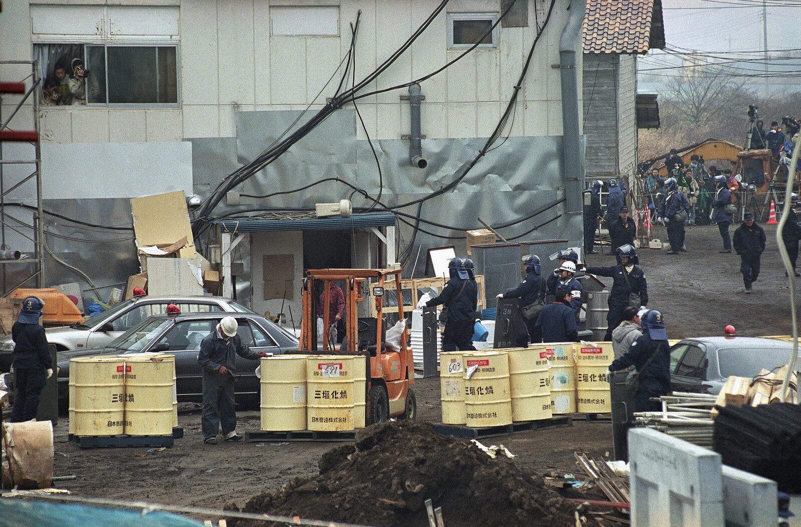 FILE - Aum Shinrikyo members look out from a window to observe the fourth-day of a police raid operation at No. 6 Satian, one of the doomsday cult's communes near Mount Fuji in Kamikuishiki, west of Tokyo, March 25, 1995. (AP Photo/Hiroshi Otabe, File)