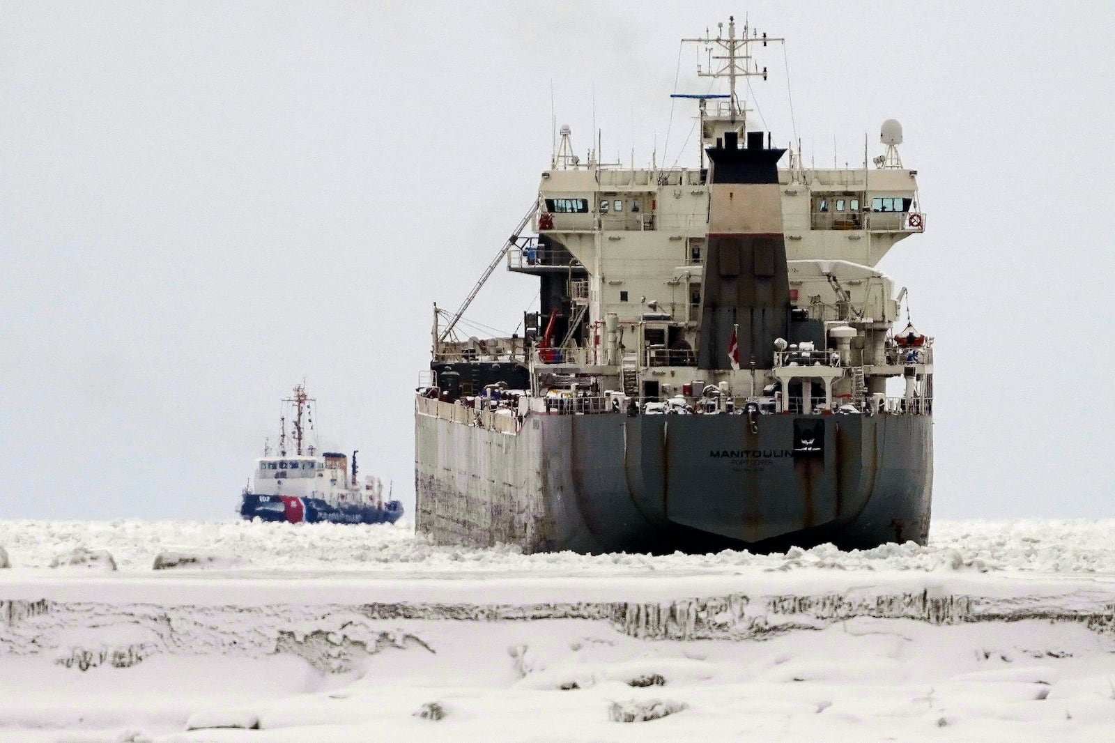 The U.S. Coast Guard Cutter Bristol Bay, left, breaks ice, Friday, Jan. 24, 2025, on Lake Erie around the lake freighter Manitoulin, which has been immobilized by thick lake ice since departing Buffalo on Wednesday morning, Jan. 22. (Derek Gee/The Buffalo News via AP)