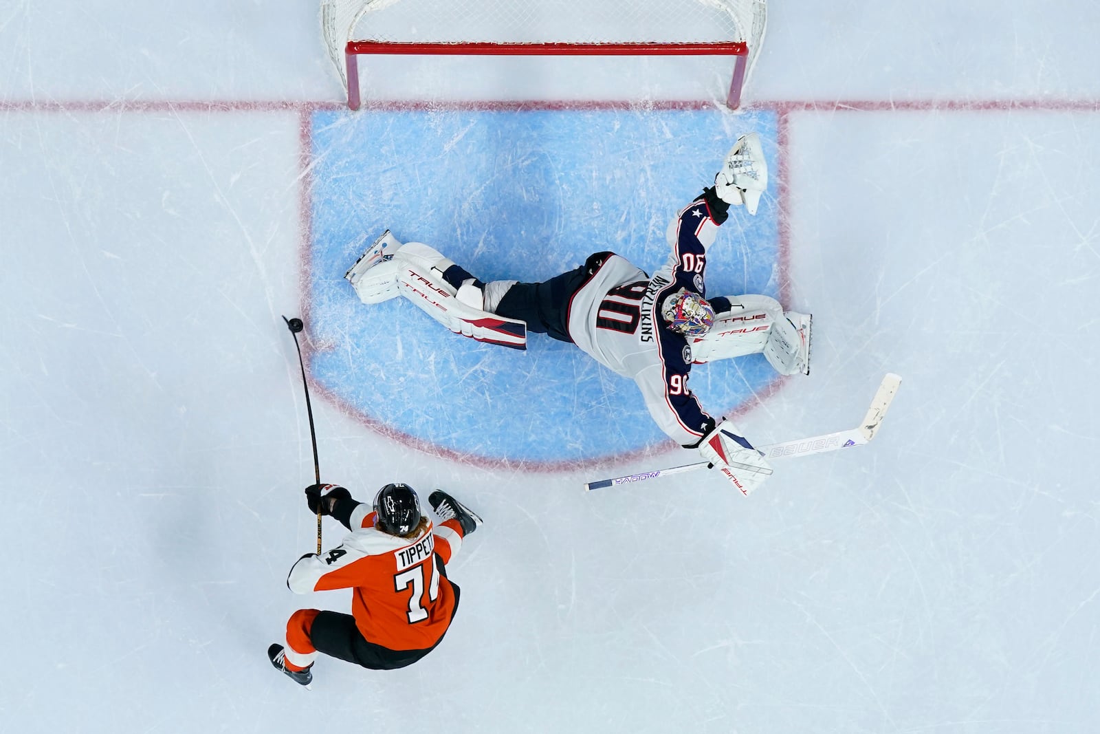 Philadelphia Flyers' Owen Tippett, left, scores the game-winning goal against Columbus Blue Jackets' Elvis Merzlikins during overtime in an NHL hockey game, Saturday, Dec. 21, 2024, in Philadelphia. (AP Photo/Matt Slocum)