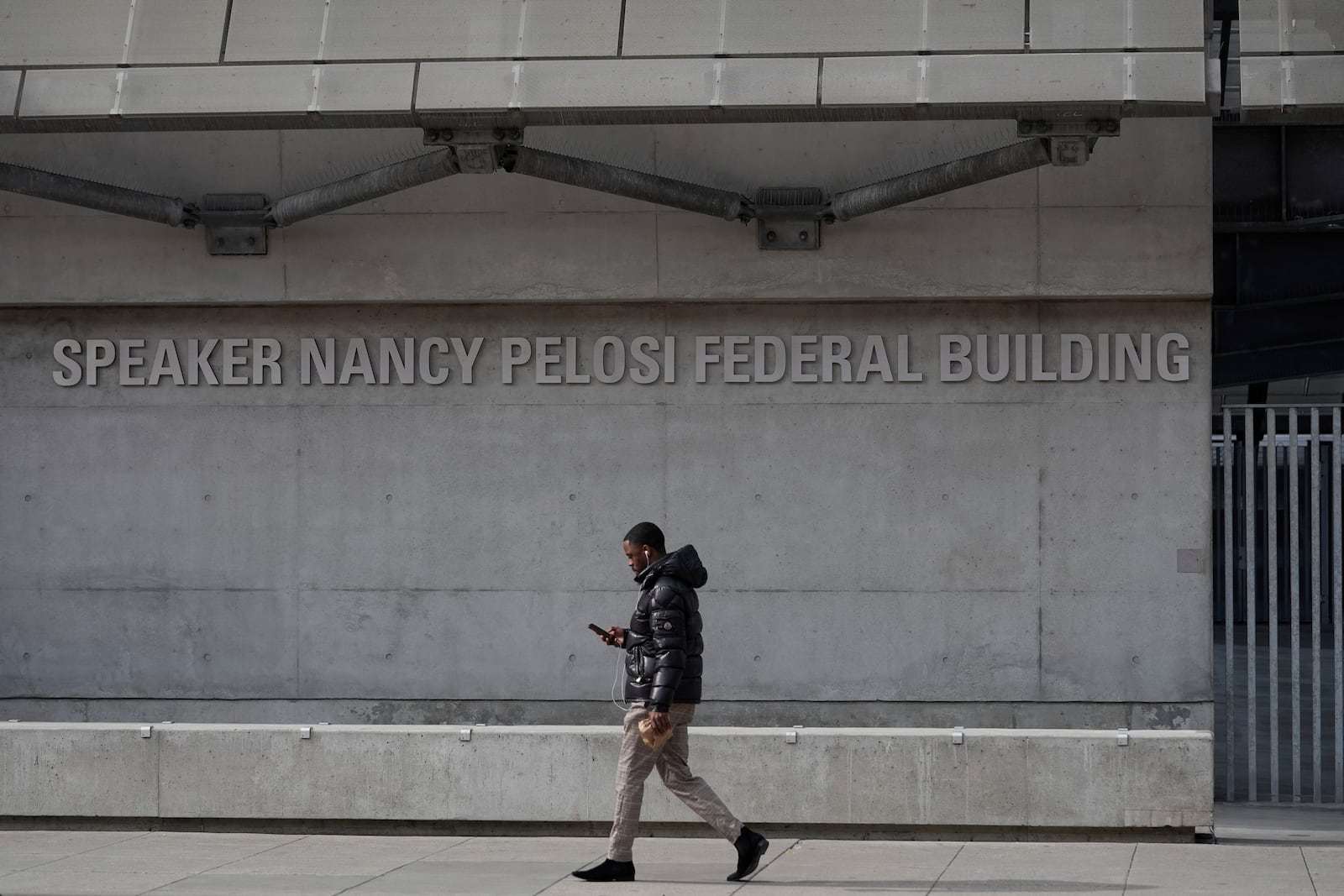 A pedestrian walks by the Speaker Nancy Pelosi Federal Building in San Francisco, Tuesday, March 4, 2025. (AP Photo/Godofredo A. Vásquez)