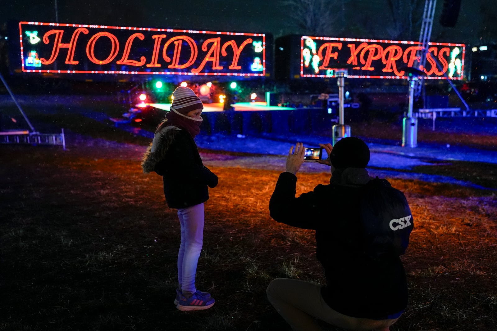 Eden Jordan, left, poses for her father Tim Jordan, right, in front of the CSX Holiday Express, Thursday, Nov. 21, 2024, in Erwin, Tenn. The railway company held a celebration and concert for the town affected by Hurricane Helene. (AP Photo/George Walker IV)