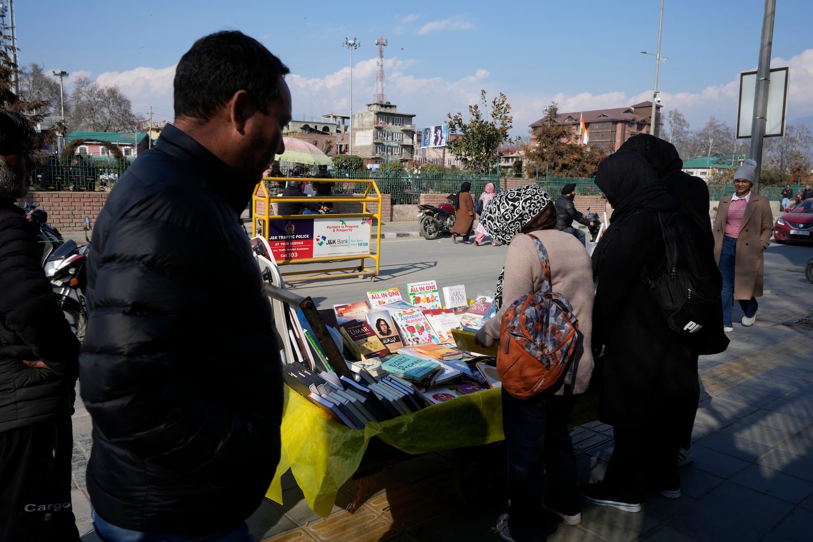 People buy books displayed for sale on a handcart in Srinagar, Indian controlled Kashmir, Monday, Feb. 17, 2025. (AP Photo/Mukhtar Khan)