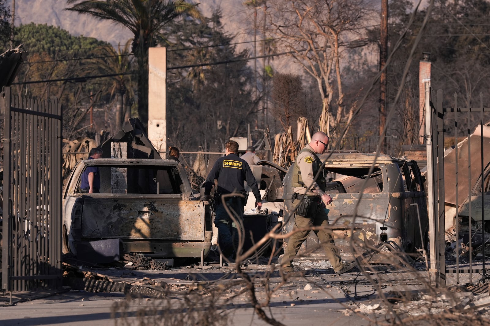 A medical examiner and sheriff's deputies check on a home destroyed by the Eaton Fire on Saturday, Jan. 11, 2025, in Altadena, Los Angeles. (AP Photo/Mark J. Terrill)