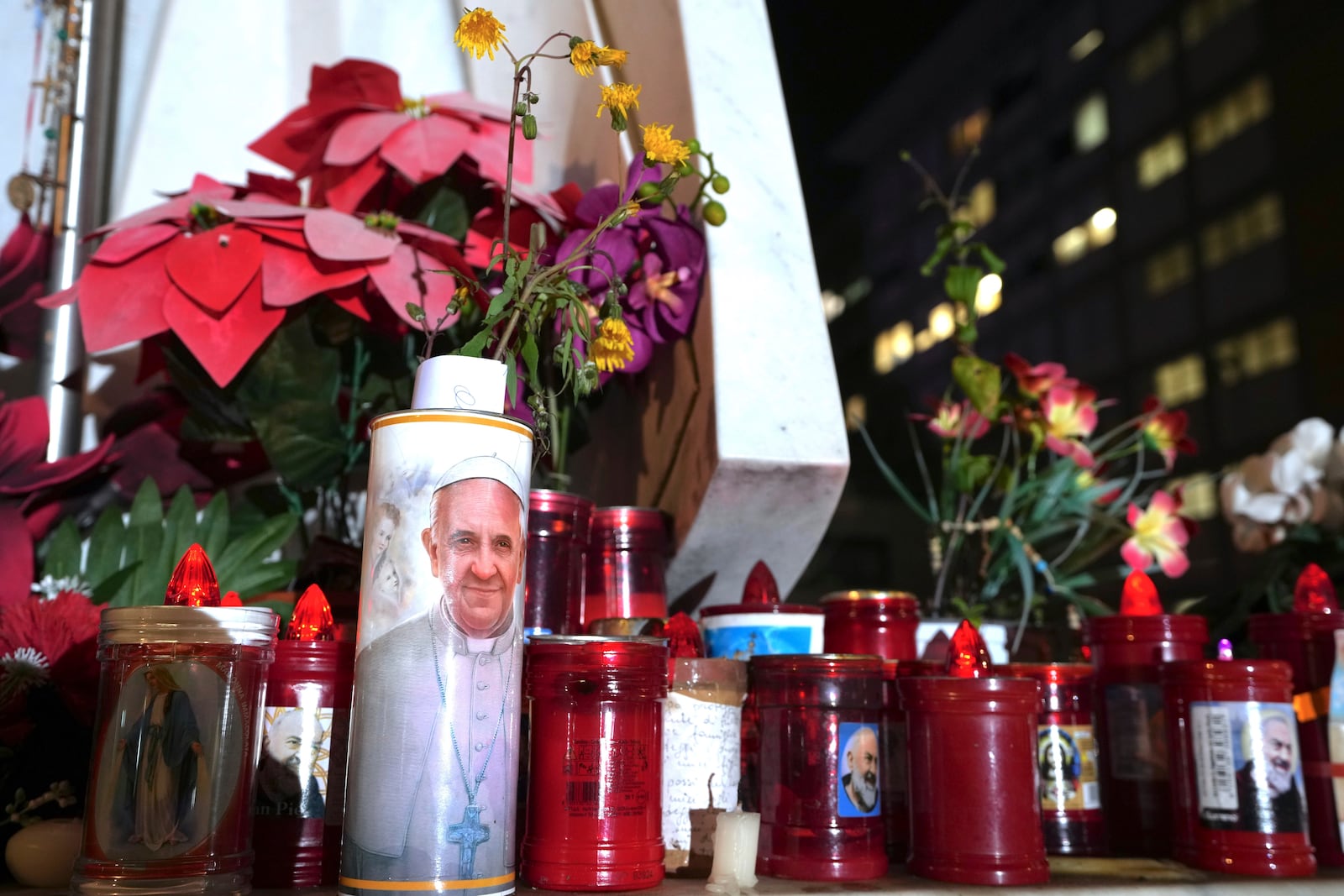 Candles are left at the foot of a marble statue of late Pope John Paul II outside the Agostino Gemelli Polyclinic in Rome where Pope Francis is being treated for pneumonia, Thursday, Feb. 20, 2025. (AP Photo/Domenico Stinellis)