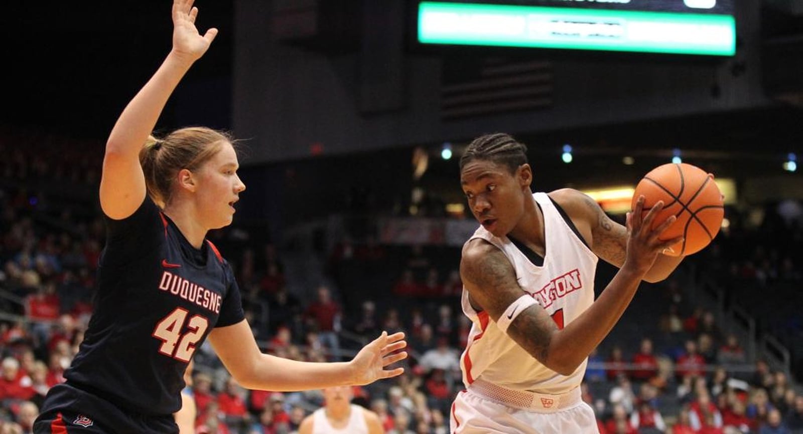 Duquesne’s Kadri-Ann Lass (42) guards Dayton’s Alex Harris during a game at the University of Dayton Arena on Jan. 31. The visiting Dukes lost 79-70. DAVID JABLONSKI/STAFF