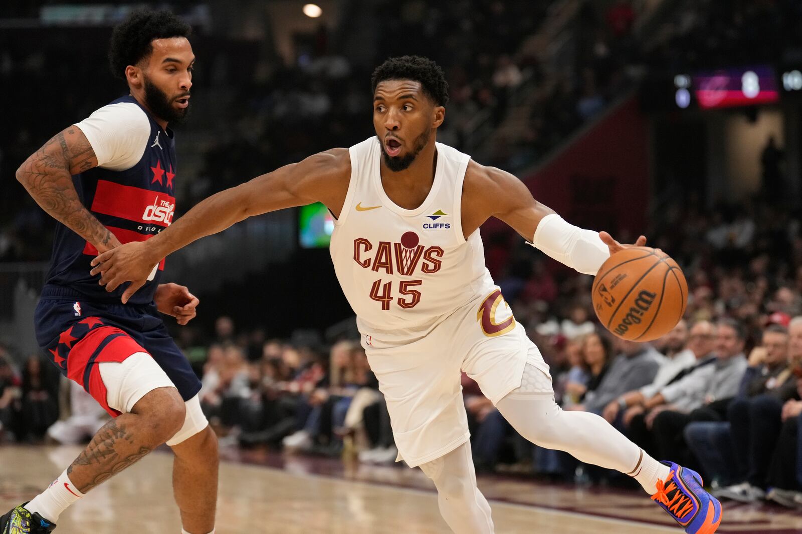 Cleveland Cavaliers guard Donovan Mitchell (45) drives around Washington Wizards forward Justin Champagnie, left, in the first half of an NBA basketball game, Friday, Dec. 13, 2024, in Cleveland. (AP Photo/Sue Ogrocki)