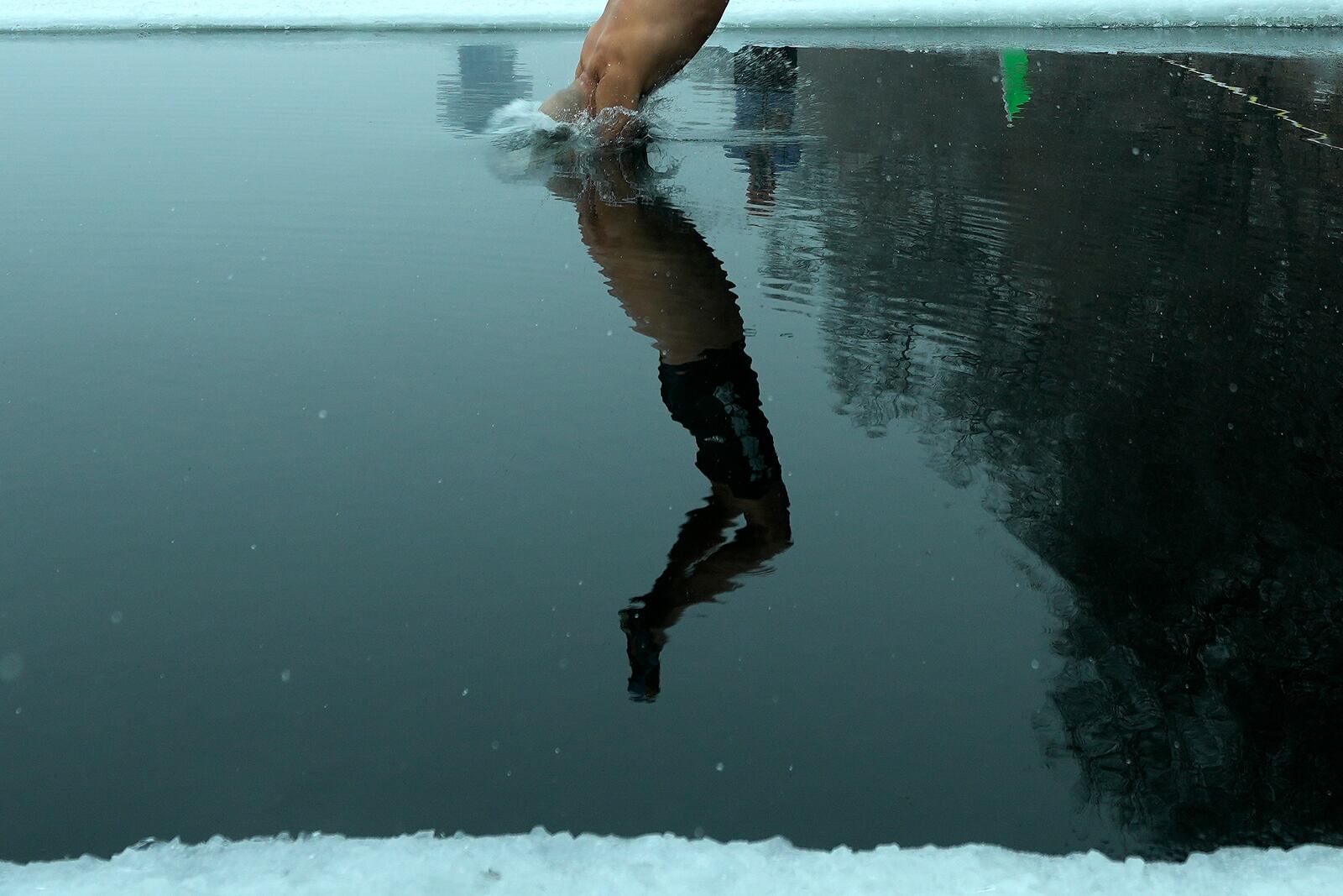 A resident jumps into a pool carved from ice on the frozen Songhua river in Harbin in northeastern China's Heilongjiang province, Tuesday, Jan. 7, 2025. (AP Photo/Andy Wong)