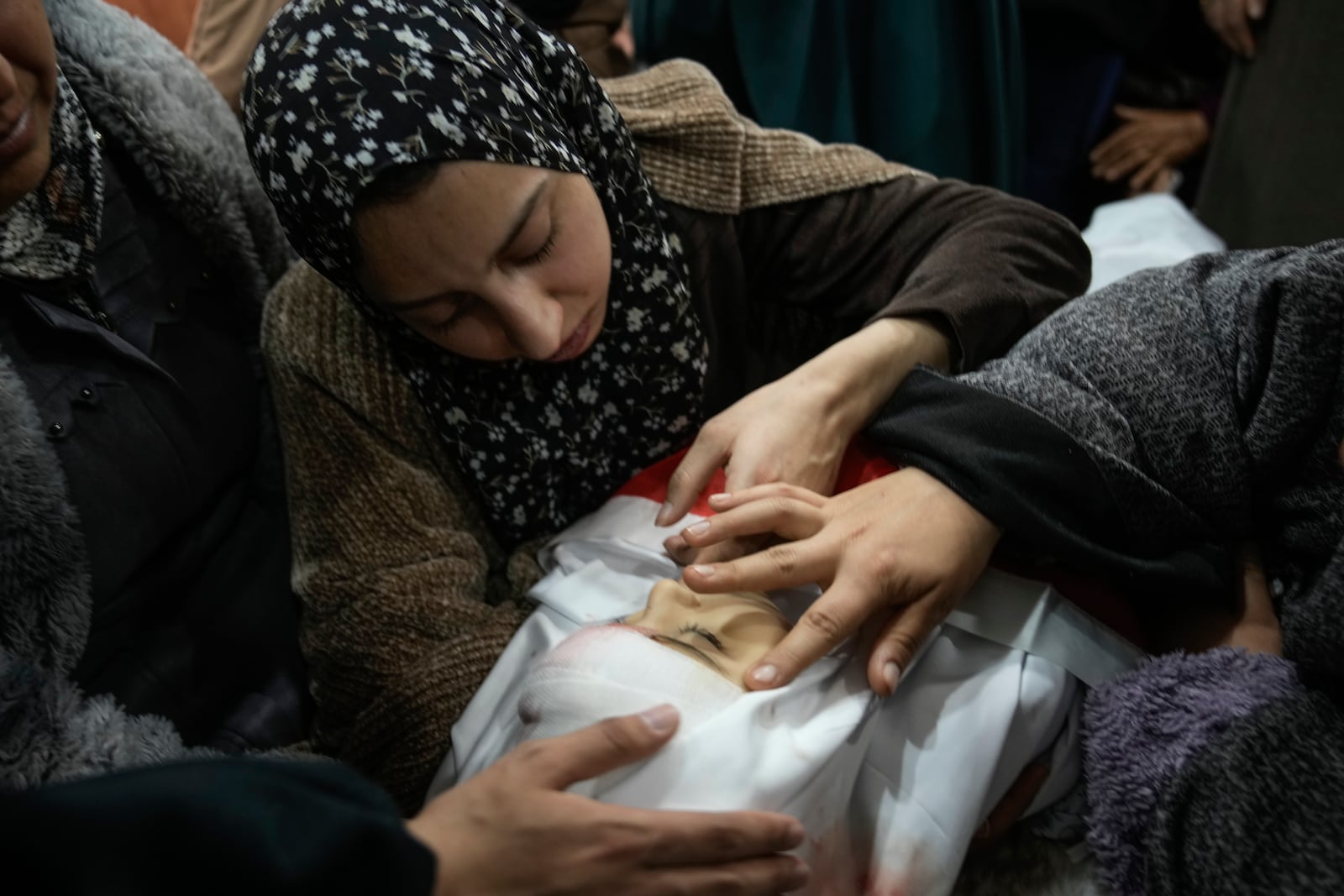 Tima Al-Khatib and another mourner gently caresse the face of her 2-year-old daughter, Laila, during her funeral in the West Bank village of Al-Shuhada, near Jenin, Sunday Jan. 26, 2025. According to the Palestinian health officials she was shot in the head by Israeli forces during an army operation in the area. Israel's military said it was reviewing the incident.(AP Photo/Majdi Mohammed)