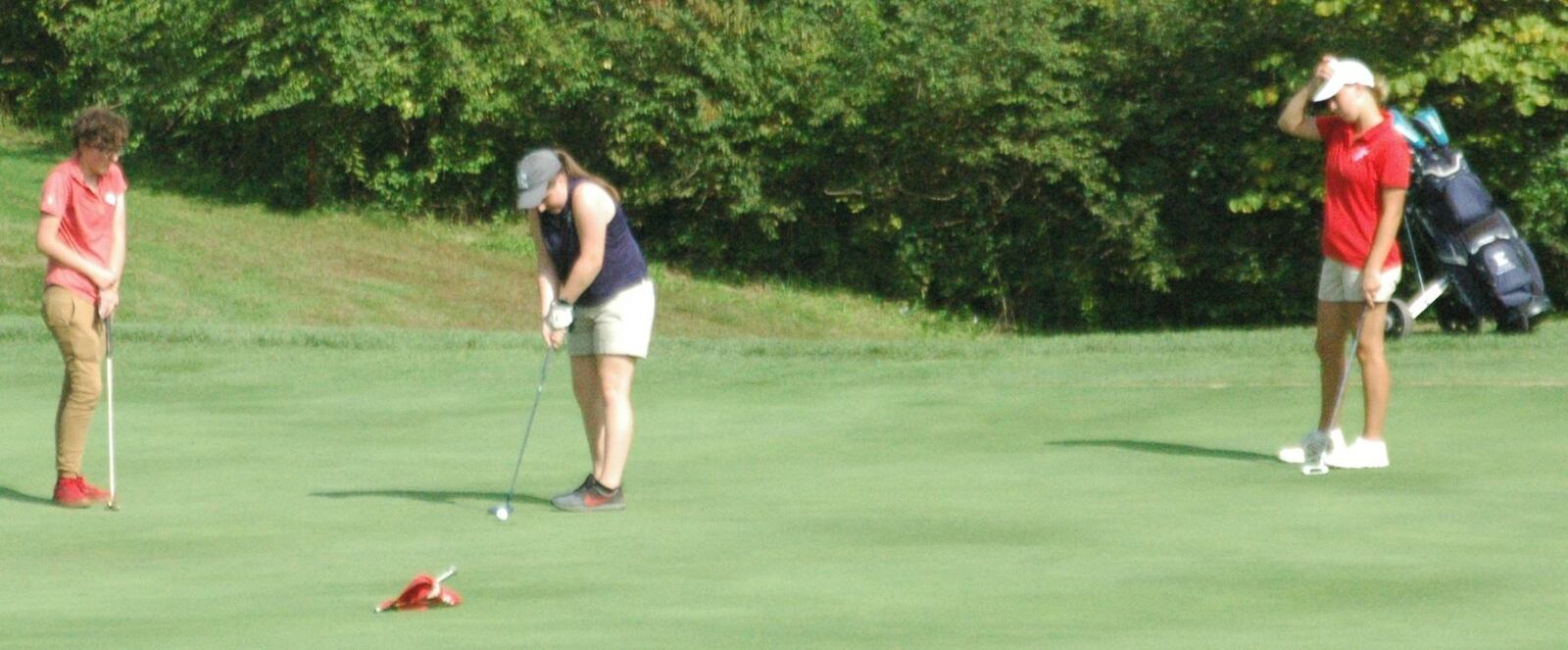 Franklin’s Allie Miller (left) and Fairfield’s Luci Stangby (right) watch Edgewood’s Samantha Schatzle complete her round on the ninth green Monday during the Division I sectional girls golf tournament at Walden Ponds Club in Fairfield Township. RICK CASSANO/STAFF