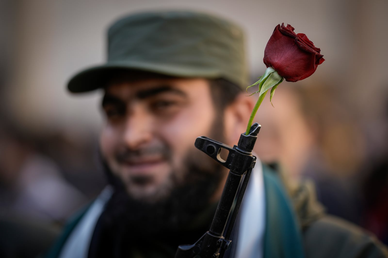 FILE - A Syrian fighter holds a gun with a flower placed in the barrel, as people gather for Friday prayers at the Umayyad mosque in Damascus, Syria, Friday, Dec. 13, 2024. (AP Photo/Leo Correa, File)