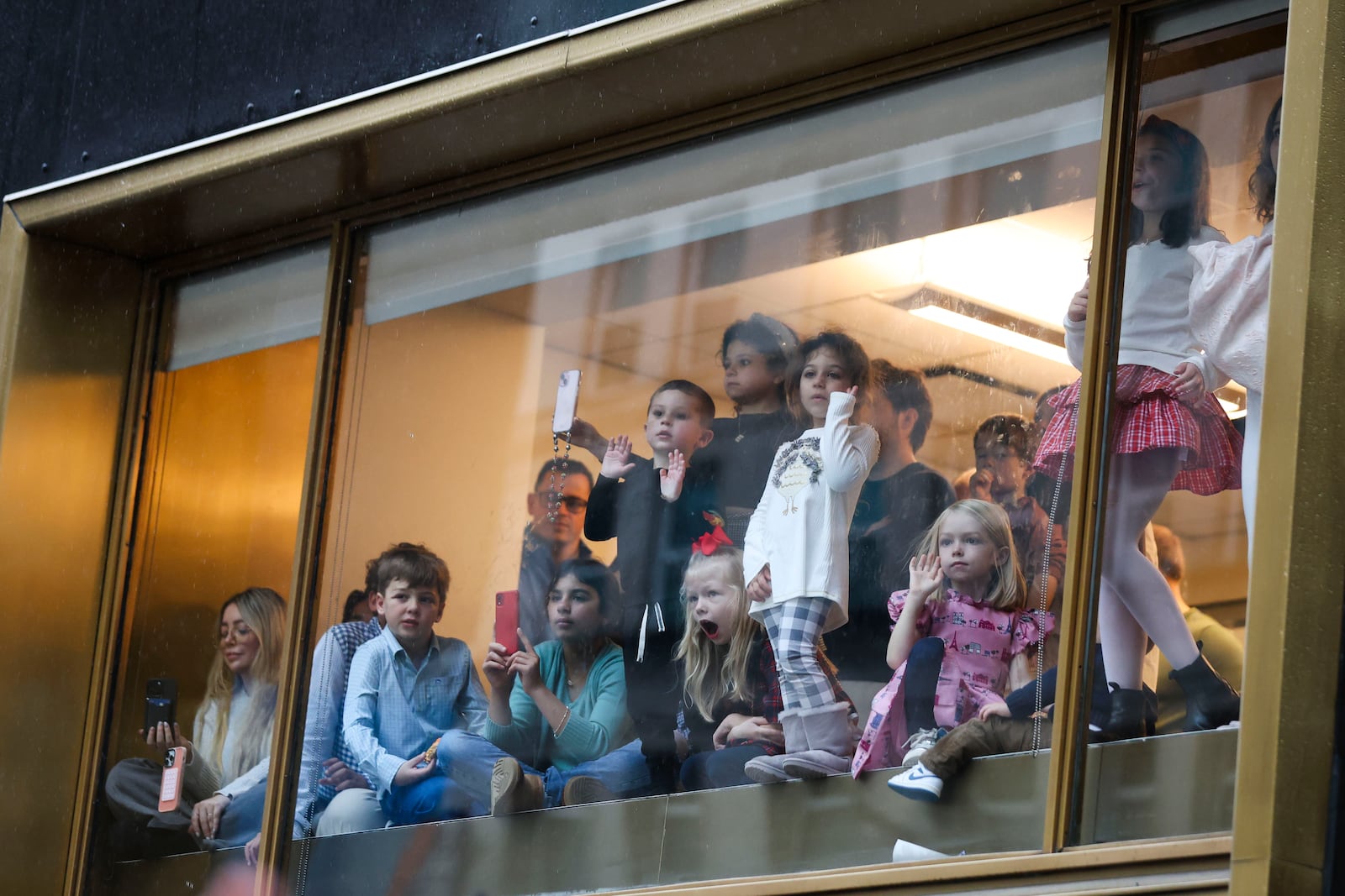 People watch from a window inside as the Macy's Thanksgiving Day parade goes by, Thursday, Nov. 28, 2024, in New York. (AP Photo/Heather Khalifa)