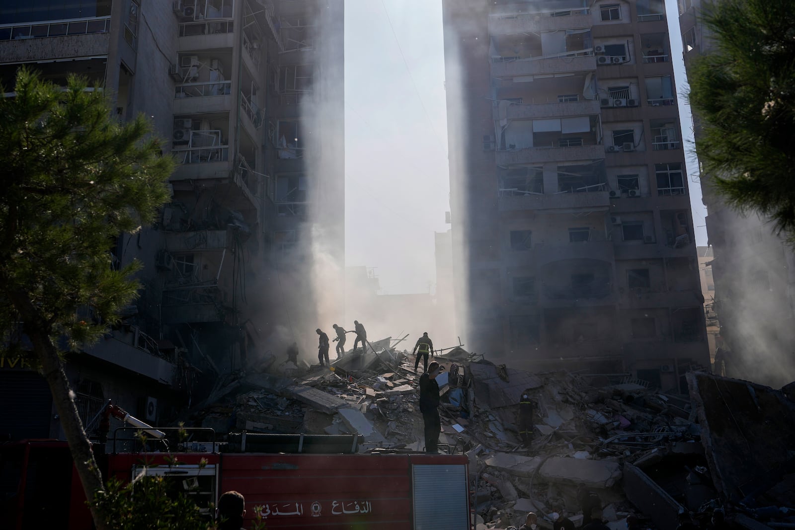 Civil defense workers extinguish a fire as smoke rises from the site of an Israeli airstrike in Tayouneh, Beirut, Lebanon, Friday, Nov. 15, 2024. (AP Photo/Hassan Ammar)