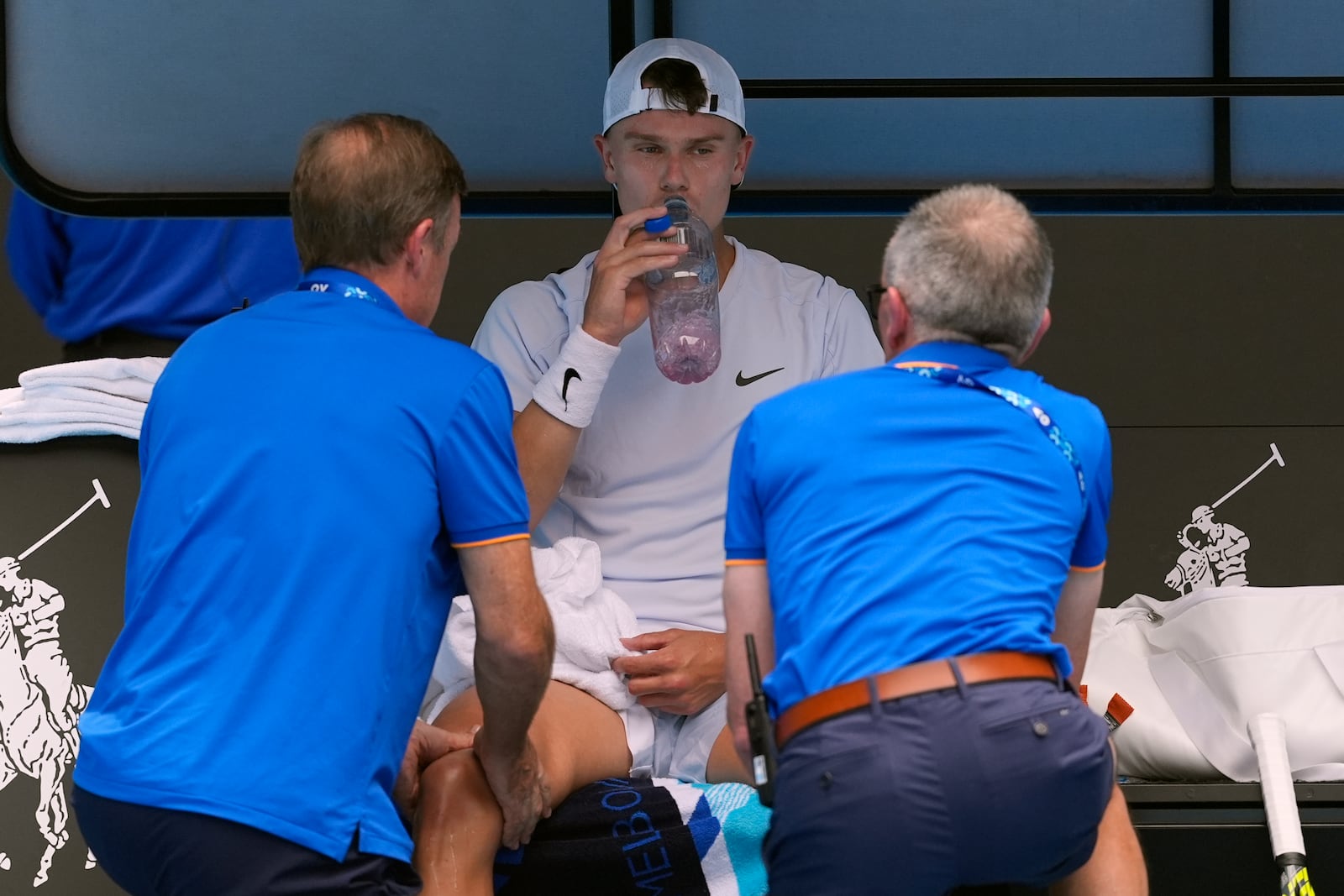 Holger Rune of Denmark receives treatment during his fourth round match against Jannik Sinner of Italy at the Australian Open tennis championship in Melbourne, Australia, Monday, Jan. 20, 2025. (AP Photo/Asanka Brendon Ratnayake)