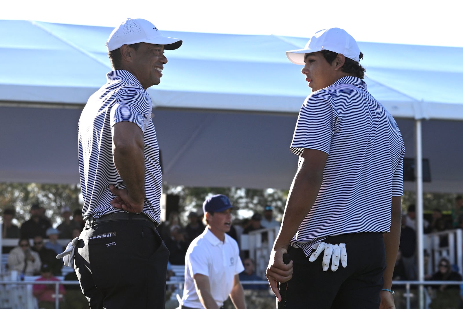 Tiger Woods, left, talks with his son Charlie Woods, right, after finishing on the 18th green during the first round of the PNC Championship golf tournament, Saturday, Dec. 21, 2024, in Orlando. (AP Photo/Phelan M. Ebenhack)