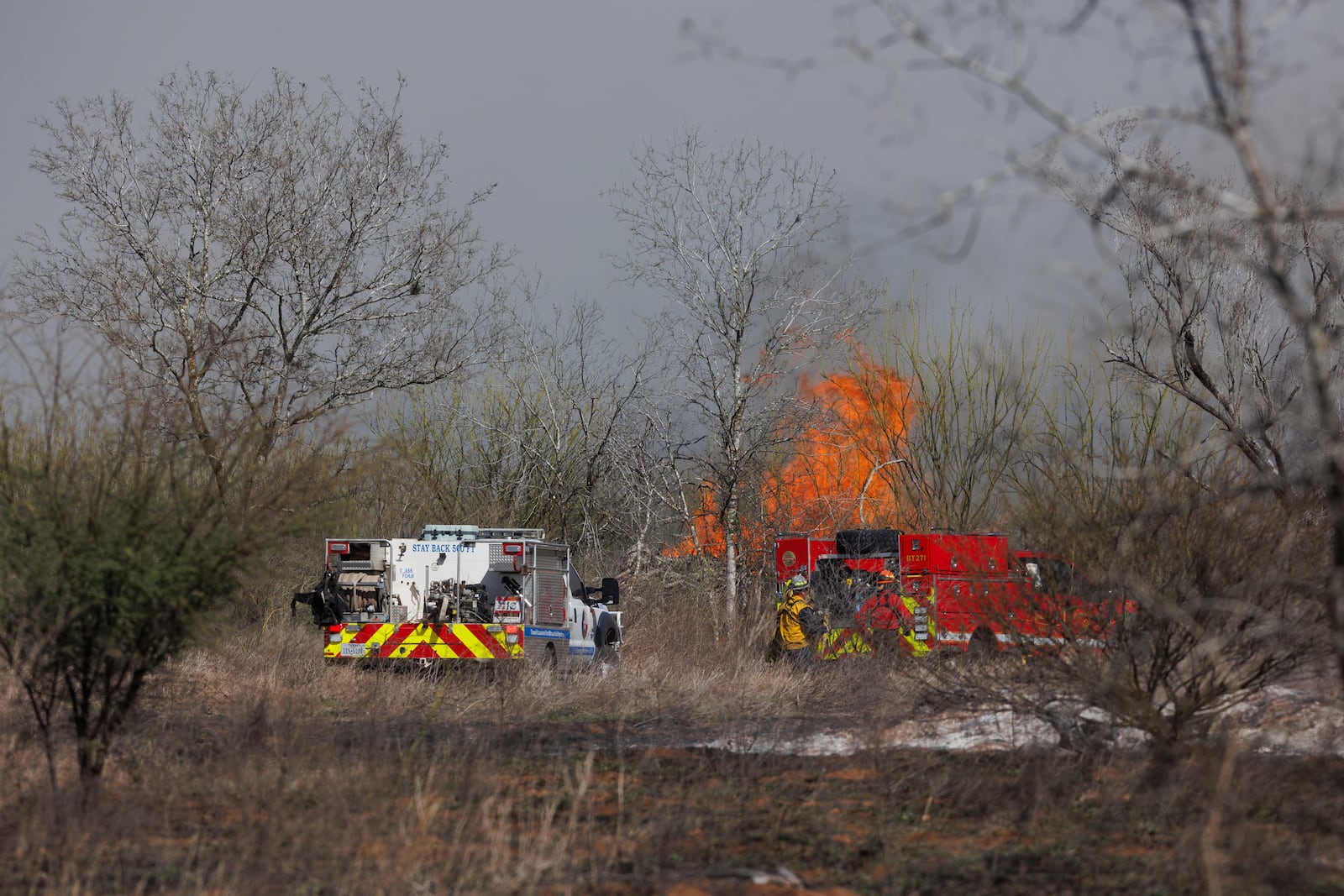 Firefighters work to put out a brush fire in a field along Southton Road, near Interstate 37, on the far southeast side of San Antonio, Tuesday, March 4, 2025. (Sam Owens/The San Antonio Express-News via AP)