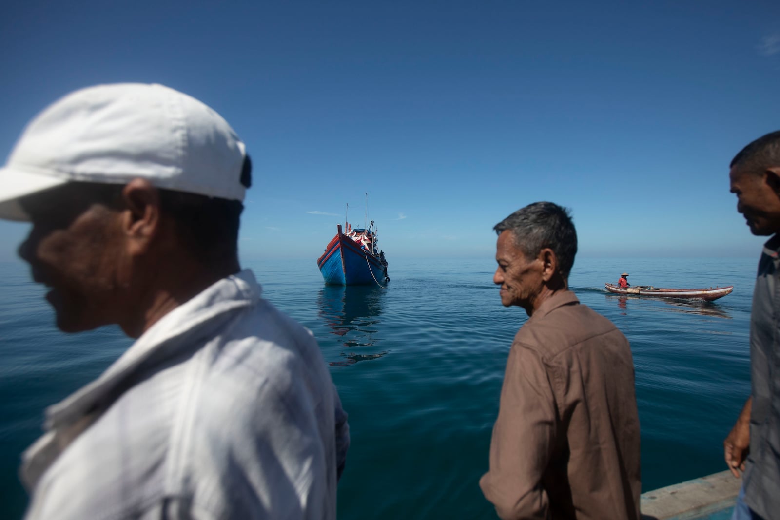 Acehnese men inspect a boat carrying Rohingya refugees anchored in the waters near the coast of Labuhan Haji, Aceh province, Indonesia, Tuesday, Oct. 22, 2024. (AP Photo/Binsar Bakkara)