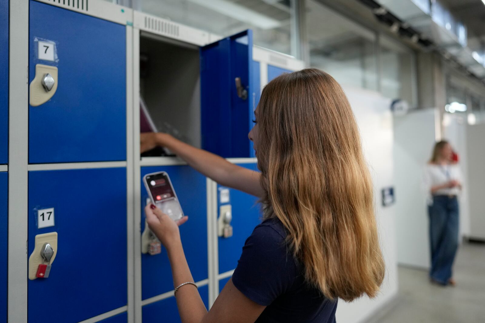 A student stores her mobile phone in a locker at Porto Seguro School in Sao Paulo, Thursday, Feb. 6, 2025, before heading to class under a new law restricting their use in schools. (AP Photo/Andre Penner)