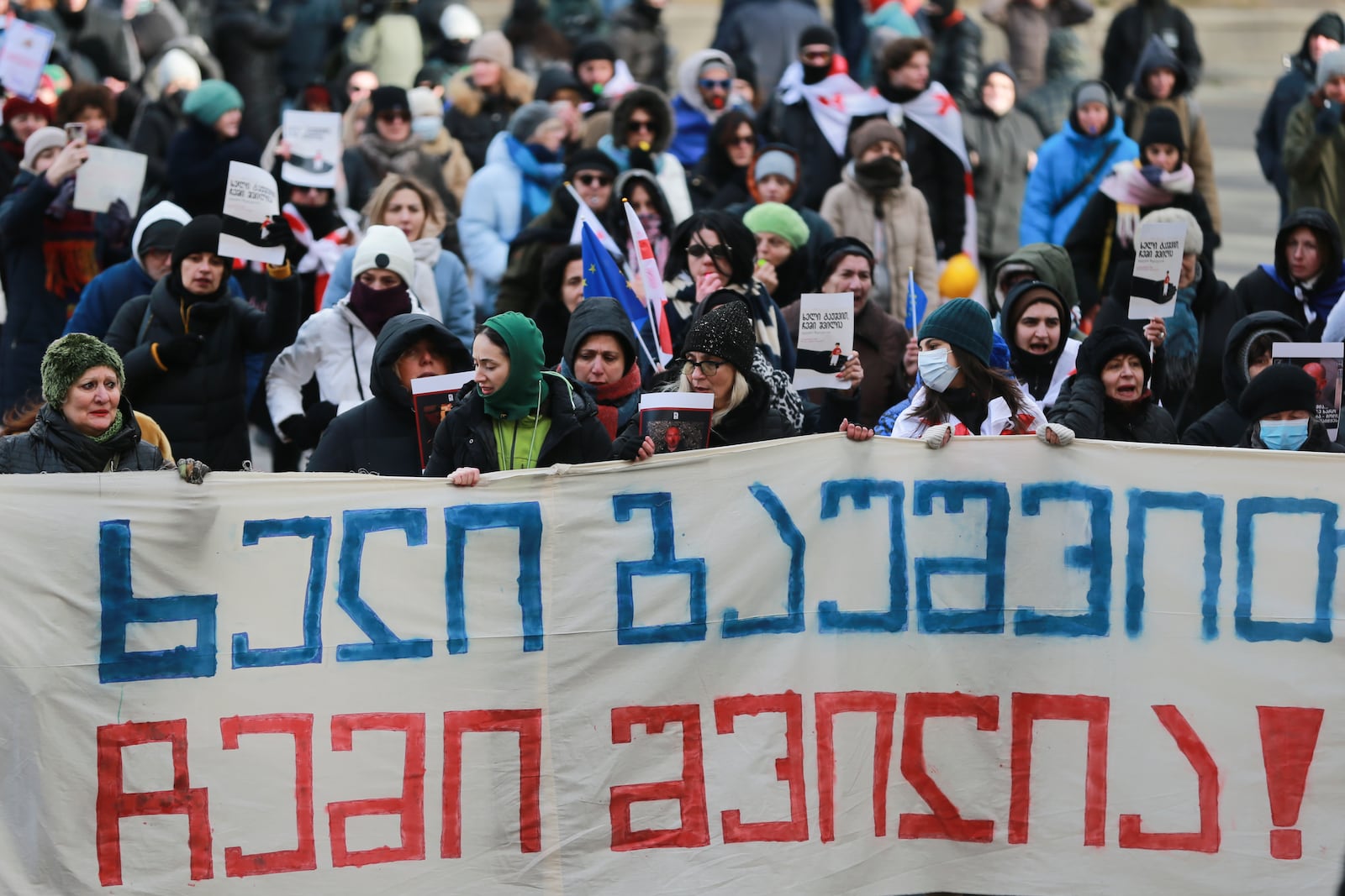 People hold a banner saying "Hands off my child" in Georgian,protesting outside of the Georgian parliament as the parliament begins the procedure of the presidential elections, in Tbilisi, Georgia, Saturday, Dec. 14, 2024. (AP Photo/Zurab Tsertsvadze)