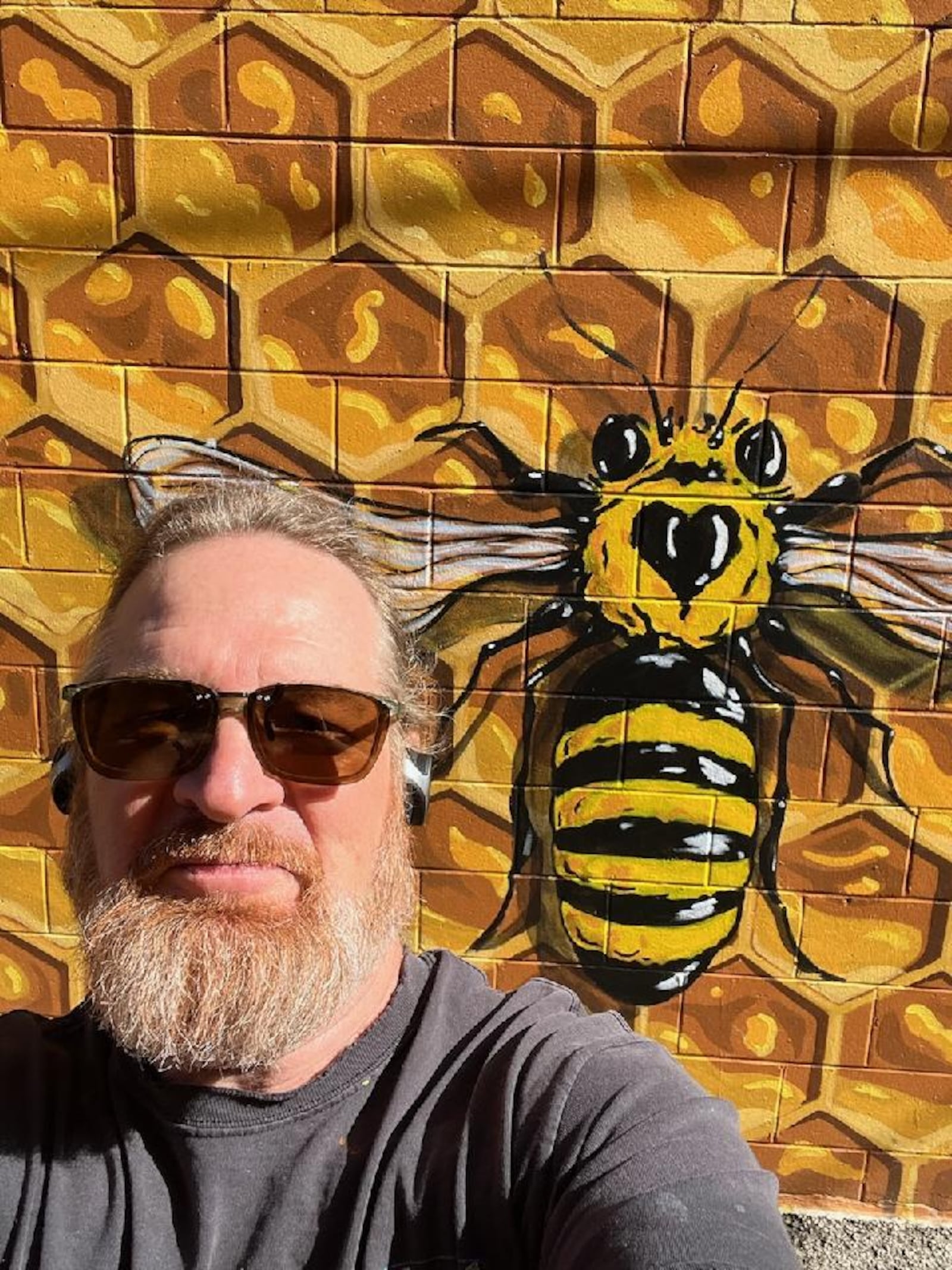 Artist Joe Prescher takes a selfie in front of the Oxford "Hive" mural, which is located off High Street in Uptown Oxford.