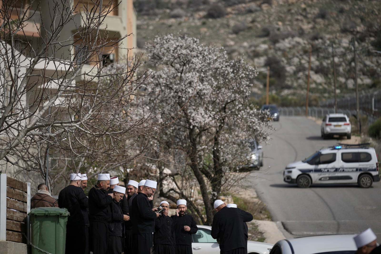 Druze clerics stand near the border, as they wait for buses carrying members of the Syrian Druze community to cross from Syria in the village of Majdal Shams, in the Israeli-controlled Golan Heights, Friday, March 14, 2025. (AP Photo/Leo Correa)