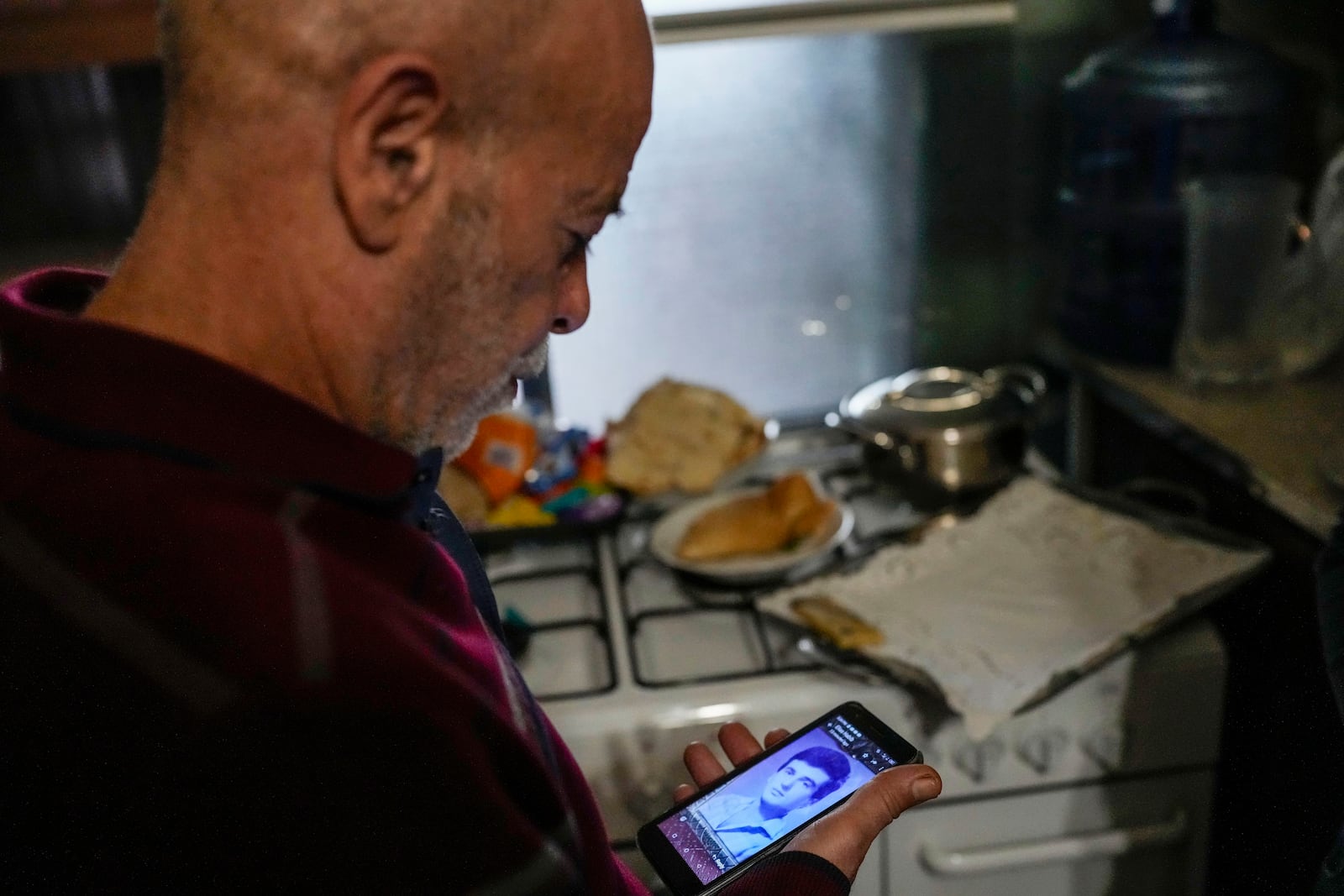 Suheil Hamwi, who spent 32 years in prison in Syria, reacts as a man shows him a picture of a missing Lebanese prisoner inside Syria, at Hamwi's home in Chekka, Lebanon, Tuesday, Dec. 10, 2024. (AP Photo/Hassan Ammar)