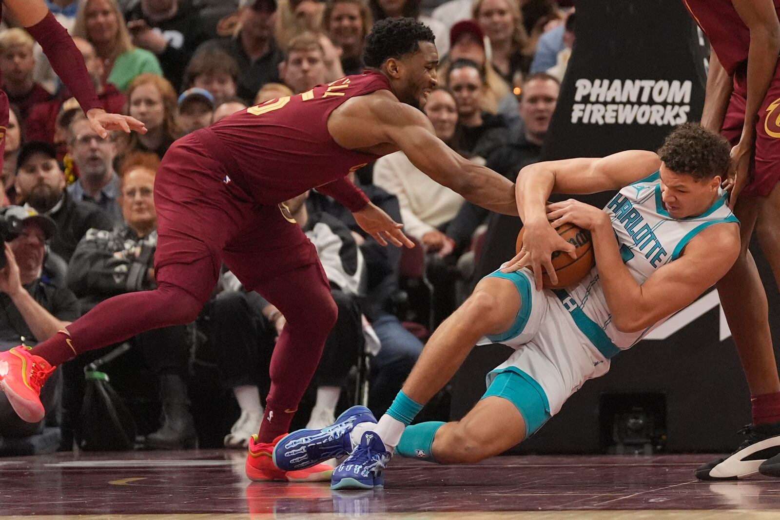 Cleveland Cavaliers guard Donovan Mitchell, left, forces a jump ball with Charlotte Hornets forward Tidjane Salaun, right, in the first half of an NBA basketball game, Sunday, Jan. 5, 2025, in Cleveland. (AP Photo/Sue Ogrocki)