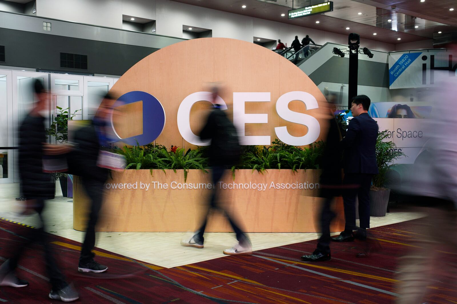 People walk by a sign ahead of the CES tech show Monday, Jan. 6, 2025, in Las Vegas. (AP Photo/John Locher)