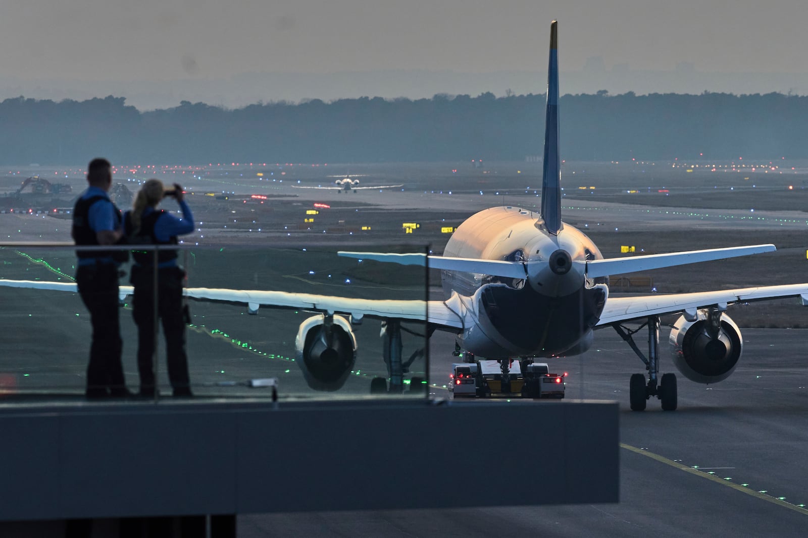 Police officers watch aircrafts take their parking positions at the airport in Frankfurt, Germany, Sunday, March 9, 2025, the evening before a warning strike of all major German airports. (AP Photo/Michael Probst)