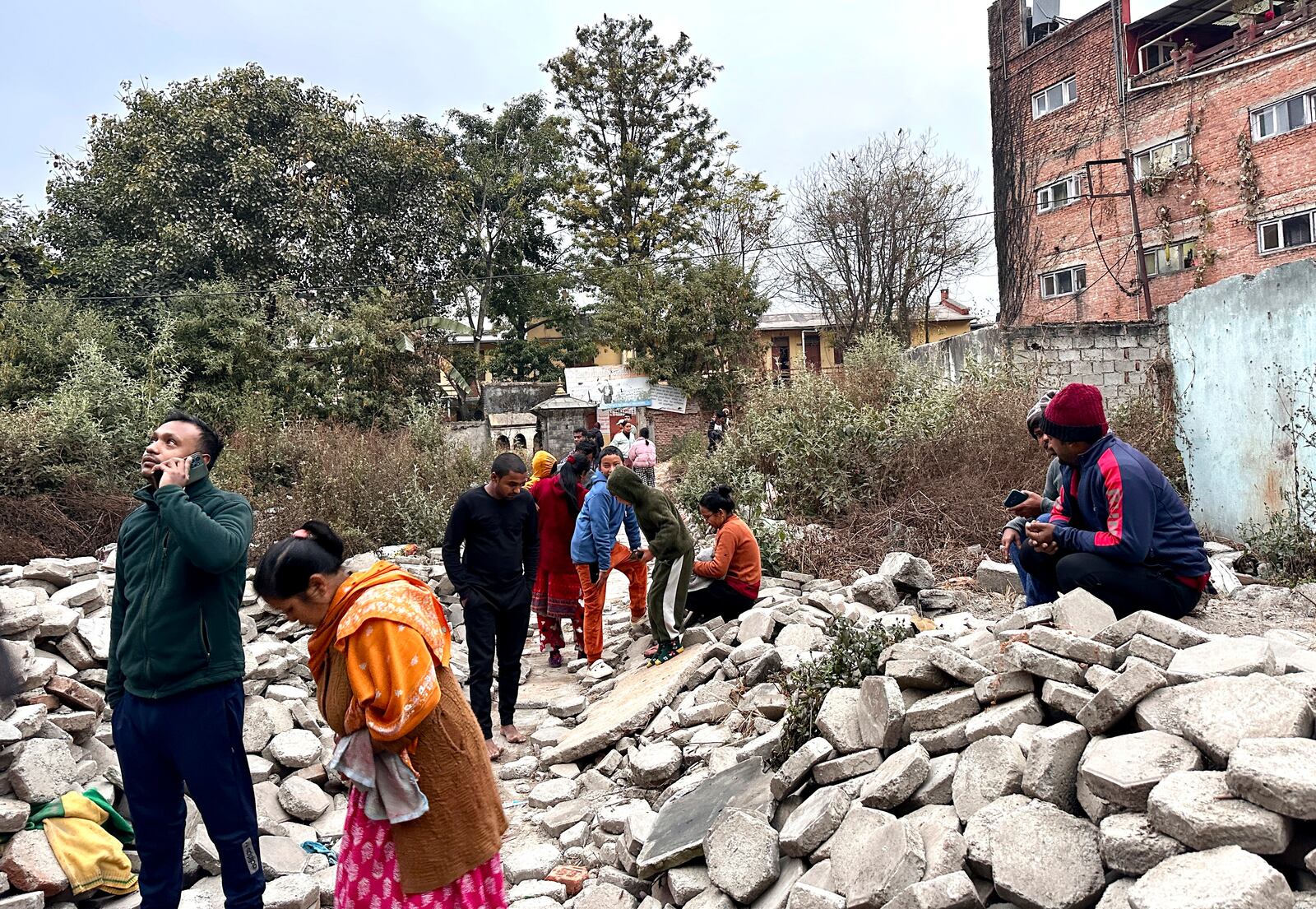 Nepalese people look on after rushing out of their homes after experiencing an earthquake in Kathmandu, Nepal, Tuesday, Jan.7, 2025. (AP Photo/Sunil Sharma)