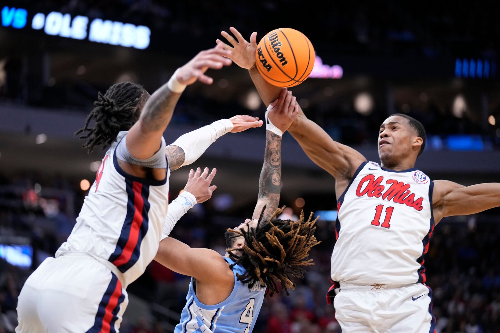 Mississippi guard Matthew Murrell (11) blocks a shot by North Carolina guard RJ Davis (4) as Mississippi guard Dre Davis, left, also reaches for the ball during the second half in the first round of the NCAA college basketball tournament, Friday, March 21, 2025, in Milwaukee. (AP Photo/Kayla Wolf)