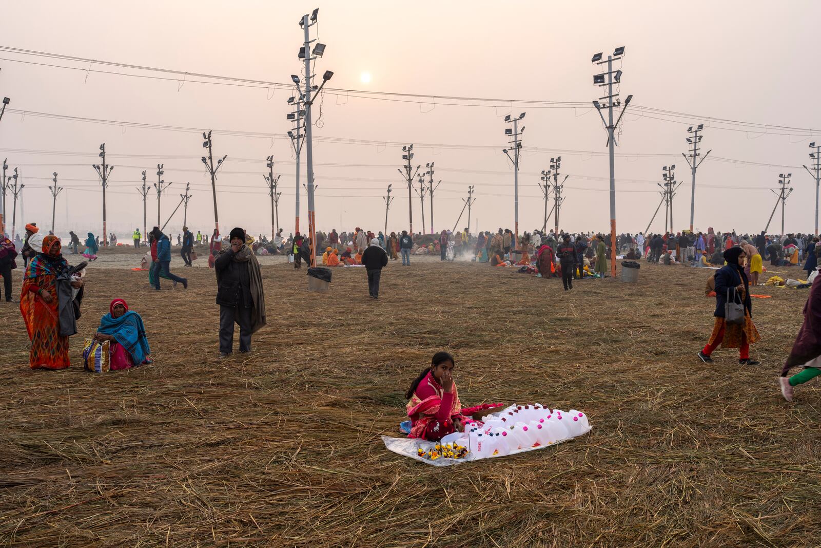 A woman sells empty plastic containers as devotees arrive to bathe at the confluence of the Ganges, the Yamuna and the mythical Saraswati rivers, a day before the official beginning of the 45-day-long Maha Kumbh festival, in Prayagraj, India, Sunday, Jan. 12, 2025. (AP Photo/Ashwini Bhatia)